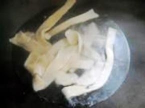 抻面时，锅中烧开水，顺势下入面片。