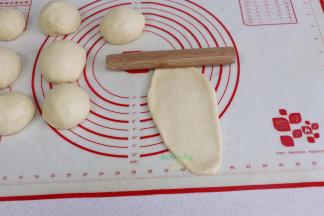 取一块面团，压扁，擀面杖从中间往下擀，再从中间往上擀，形成椭圆形。初学者，形状不漂亮也没关系，只要味道对了就可以。