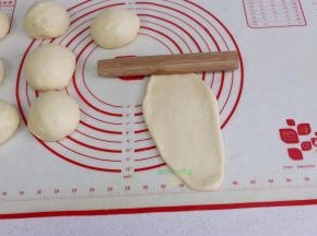 取一块面团，压扁，擀面杖从中间往下擀，再从中间往上擀，形成椭圆形。初学者，形状不漂亮也没关系，只要味道对了就可以。