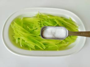 切好的莴笋丝放一勺盐，抓拌均匀腌制三分钟，再用清水清洗干净，捏干水分备用。