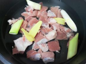 凉水入锅，加入2勺料酒、一些姜片和葱段，烧开将羊肉焯水。