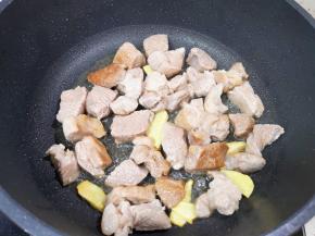 炒锅内倒适量的食用油烧热，下入姜片煎出香味，下入羊肉块翻炒至变色。