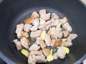炒锅内倒适量的食用油烧热，下入姜片煎出香味，下入羊肉块翻炒至变色。