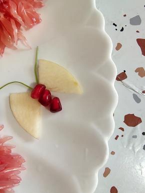 一片苹果对半切开，再对着摆放，中间放3颗石榴点缀一下，用香菜梗当蝴蝶的胡须！一只蝴蝶就做好了！