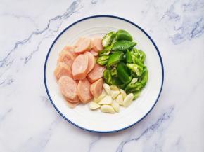 辣椒切滚刀块，香肠切片煎熟，大蒜去皮拍扁，