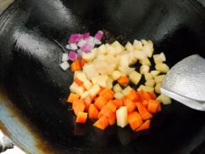 锅中余油，爆香洋葱，下土豆、胡萝卜，加少许盐翻炒均匀。