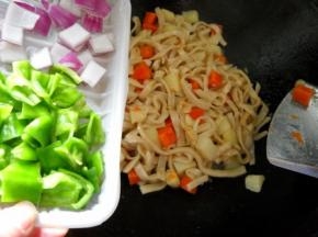 锅中水煮至快干时，将土豆胡萝卜翻炒到面条上面；倒入青椒。