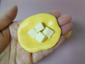 取一个小团子压扁，包入芝士片，捏紧收口继续搓成小团子。