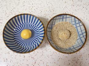 准备少许纯净水和半碗熟白芝麻，将南瓜糯米团子表面沾上水，放在芝麻碗里滚几圈，沾满芝麻。