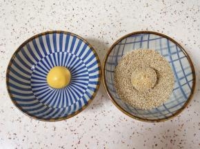 准备少许纯净水和半碗熟白芝麻，将南瓜糯米团子表面沾上水，放在芝麻碗里滚几圈，沾满芝麻。
