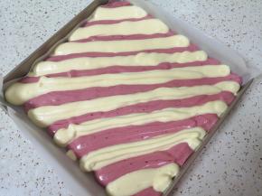 烤盘里铺上油纸，原味蛋糕糊和红色蛋糕糊相间着挤入烤盘。