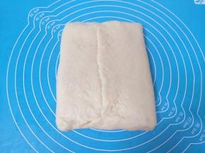 油皮面团对折将油酥面团包起来，收好接口。