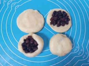 将油酥面皮擀开，包入糖纳红小豆，用虎口慢慢向上推挤收口，反过来收口朝下摆放。