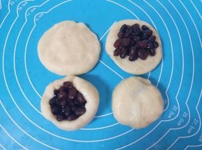 将油酥面皮擀开，包入糖纳红小豆，用虎口慢慢向上推挤收口，反过来收口朝下摆放。