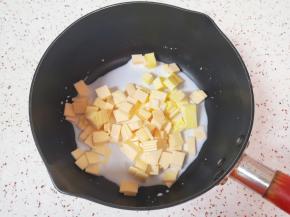 芝士片切碎，小锅里倒入牛奶，加入黄油和切碎的芝士片。