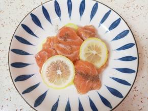 柠檬切成片，和三文鱼片一起放入盘子里，加入黑胡椒粉搅拌均匀，腌制20分钟。