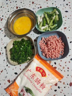 准备好所需的食材:

葱头和葱叶分开切！葱叶切成葱花，葱头切成段！火腿肠切成小丁，准备两杯广东肠粉，再把鸡蛋打散备用！