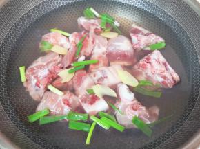 大骨头剁成小块，凉水入锅，加入葱段、姜片和2勺料酒焯水。