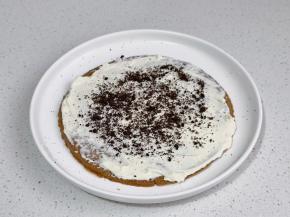 取一块饼干，涂抹一层奶油奶酪，撒奥利奥碎。