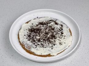 取一块饼干，涂抹一层奶油奶酪，撒奥利奥碎。