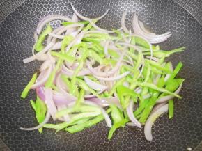 炒锅内倒适量的食用油烧热，下入洋葱和青椒丝炒出香味。