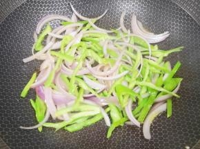 炒锅内倒适量的食用油烧热，下入洋葱和青椒丝炒出香味。