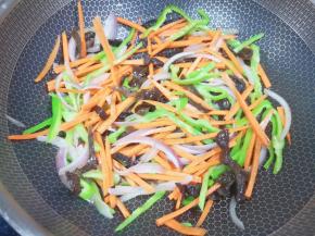 下入胡萝卜和木耳丝翻炒均匀。