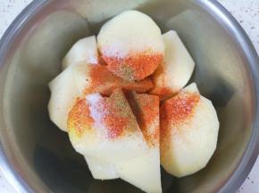 切好的土豆块放入盆里，加入3勺玉米油、半勺盐、1勺辣椒粉和1勺孜然粉。