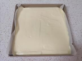 烤盘里铺上油纸，倒入蛋糕糊，轻震几下震出大气泡，用刮刀刮平表面。