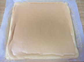 蛋糕片出炉轻震几下，带油纸一起取出，撕开油纸晾至手温。