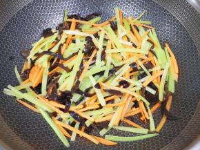 锅里继续倒油烧热，下入莴笋、胡萝卜和黑木耳翻炒均匀。