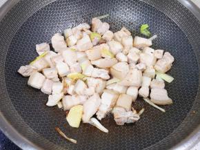 下入五花肉煸炒至表面微微焦黄。