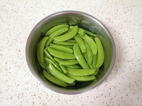 甜豆抽丝，用淡盐水浸泡10分钟左右清洗干净。