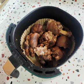 空气炸锅铺上吸油纸，把猪蹄放进去，表面喷少许油！