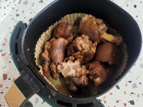 空气炸锅铺上吸油纸，把猪蹄放进去，表面喷少许油！