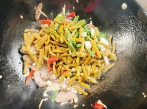 放入酸豇豆，酸辣椒和蒜苗翻炒均匀！