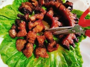 把烤好的脆皮五花肉摆放在盘子里，用干净的厨房剪刀剪成小块儿！