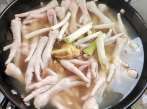 锅里烧水，放入少许盐，再往里加几滴白醋（加入白醋，可以使鸡爪焯水的时候不容易破，有劲道性，好扒！）再把鸡爪放里面，来点大块的葱姜，花椒，八角，料酒！