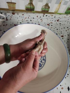 调过来！手往前推，顺着刚拉一下的那个缝儿往前推，推到前面左右推一下，然后脱骨！调过来，用手指抓住鸡爪的指尖，往前推，就这么往前窜！