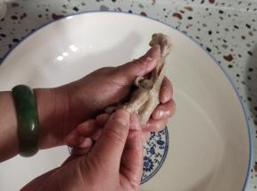 调过来！手往前推，顺着刚拉一下的那个缝儿往前推，推到前面左右推一下，然后脱骨！调过来，用手指抓住鸡爪的指尖，往前推，就这么往前窜！