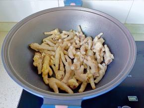 锅里放适量的食用油，加入蒜爆香后加鸡爪煸炒到表面微黄