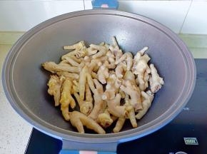 锅里放适量的食用油，加入蒜爆香后加鸡爪煸炒到表面微黄