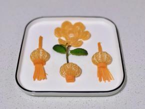 花朵中间再摆上橘子瓣，剪一条橘子皮做灯笼提手。