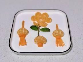 花朵中间再摆上橘子瓣，剪一条橘子皮做灯笼提手。