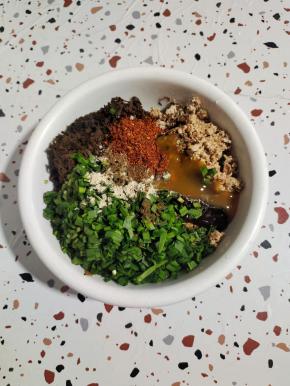 碗中放入剁碎的猪油渣，泡发好的干酸菜，韭菜（也可以换成葱花），1勺胡椒粉，1勺花椒粉，1大勺生抽，1勺蚝油，1勺太太乐鸡汁鲜，1勺辣椒面！