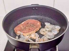 锅中喷油，放牛排和虾仁，撒黑胡椒。