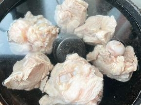 另起锅添加适量清水，放入料酒、调味盒和猪骨棒大火炖起来。