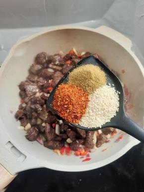 放入一把孜然粉，辣椒面和白芝麻！快速翻炒均匀！