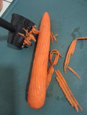 胡萝卜和黄瓜要选择小一点，直溜的！这样才好操作！先把胡萝卜用卷花刀上面刮丝的一头，把胡萝卜皮刮掉，这样卷出来的花才有层次感！