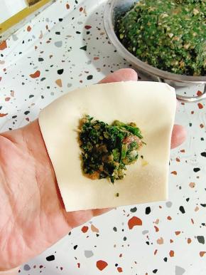 取一个饺子皮，挖一勺荠菜猪肉馅儿！